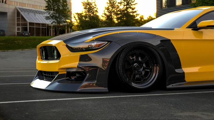 Yellow and black Mustang in a parking lot with buildings and trees in the background